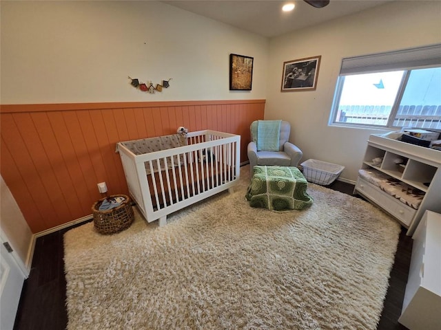 bedroom featuring wood walls and a crib