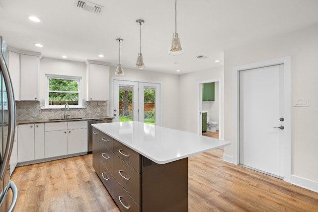 kitchen with decorative light fixtures, a kitchen island, decorative backsplash, and white cabinetry