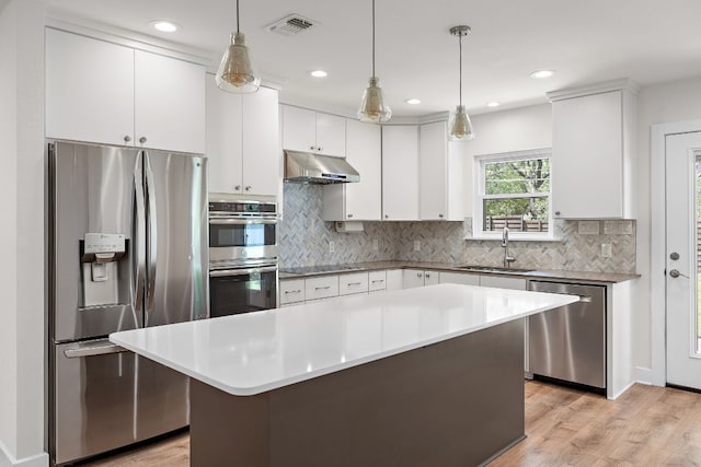 kitchen featuring a center island, sink, hanging light fixtures, white cabinets, and appliances with stainless steel finishes