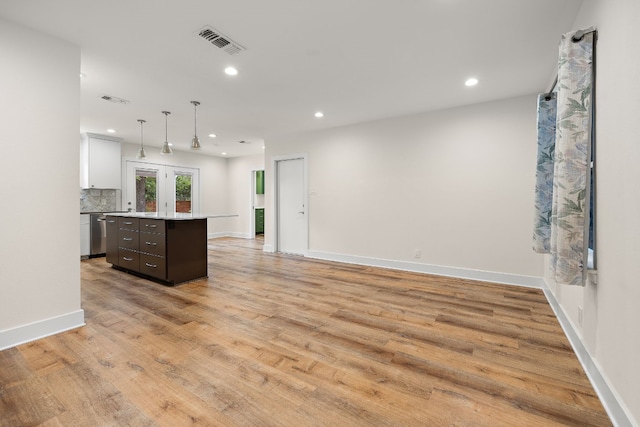 kitchen with white cabinets, hanging light fixtures, light hardwood / wood-style floors, dark brown cabinets, and a kitchen island