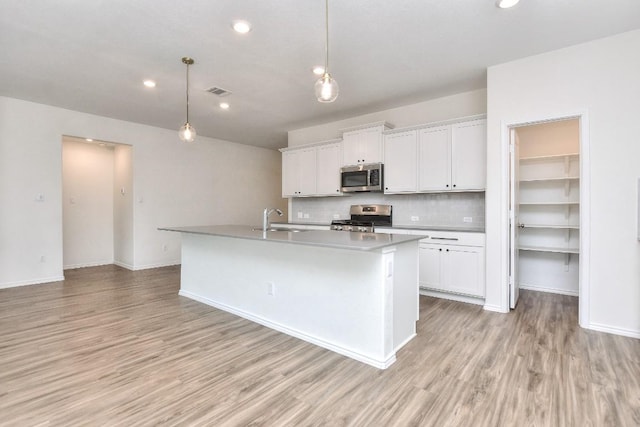 kitchen with white cabinets, an island with sink, and appliances with stainless steel finishes