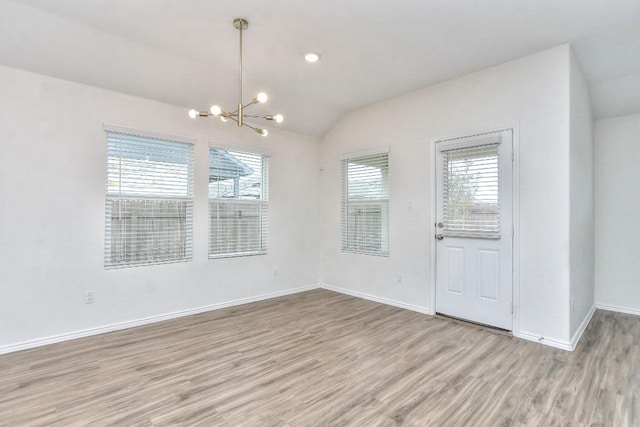 unfurnished dining area with a notable chandelier, lofted ceiling, and light hardwood / wood-style flooring