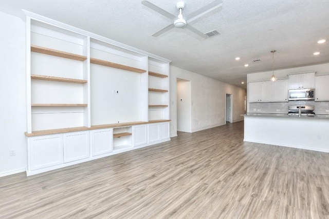 unfurnished living room featuring ceiling fan, a textured ceiling, and light wood-type flooring