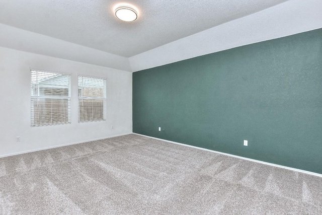 empty room featuring carpet, a textured ceiling, and lofted ceiling