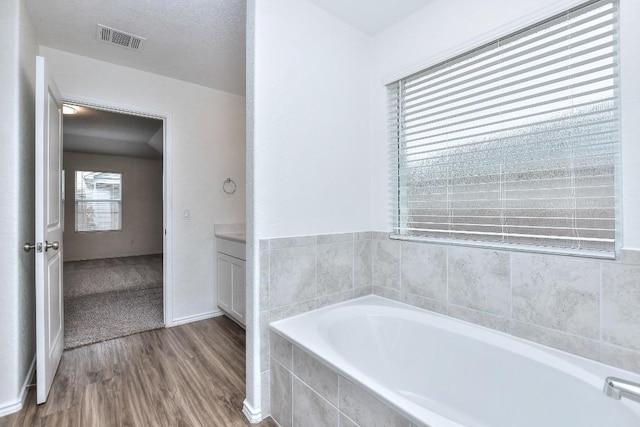 bathroom featuring vanity, wood-type flooring, and tiled bath