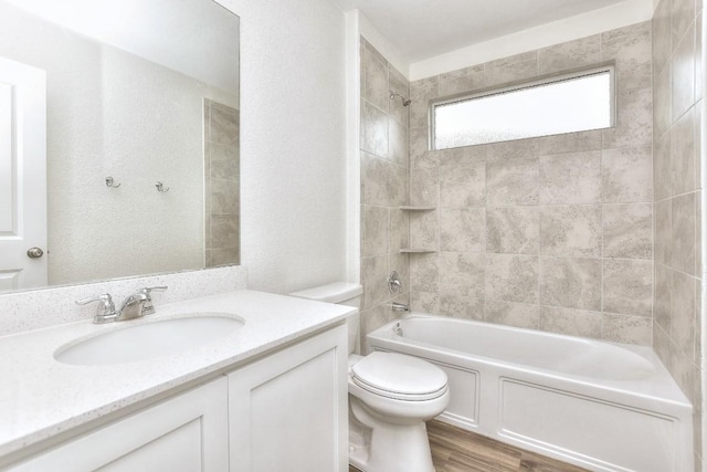 full bathroom with hardwood / wood-style floors, vanity, toilet, and tiled shower / bath