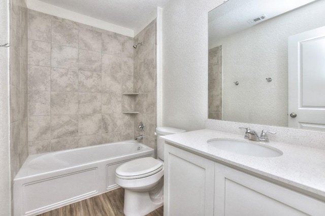 full bathroom with hardwood / wood-style floors, vanity, toilet, and tiled shower / bath