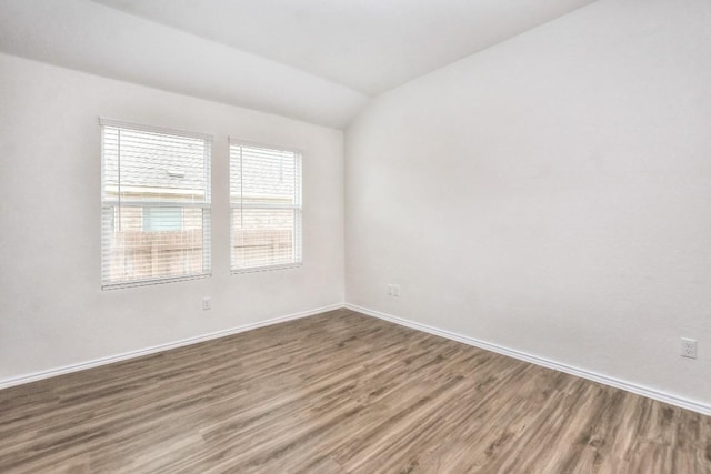 unfurnished room featuring vaulted ceiling and hardwood / wood-style flooring