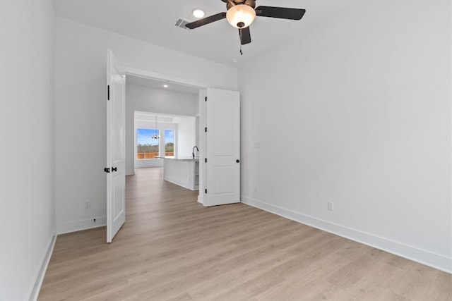 unfurnished room with visible vents, light wood-type flooring, a ceiling fan, and baseboards