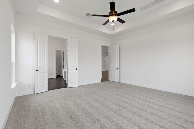 unfurnished bedroom with carpet floors, visible vents, and a raised ceiling