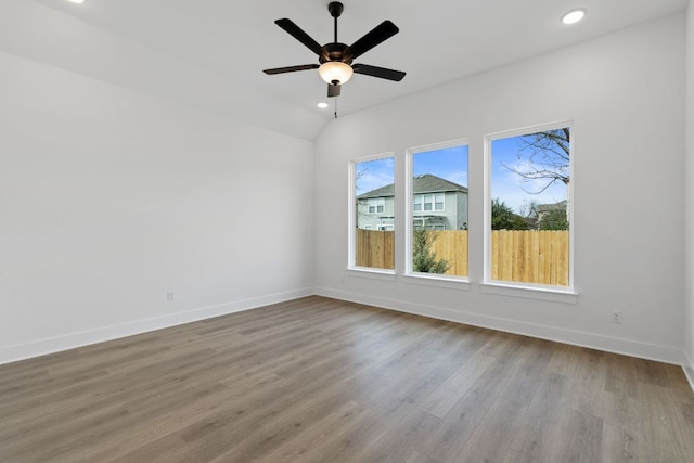 empty room with recessed lighting, lofted ceiling, ceiling fan, wood finished floors, and baseboards