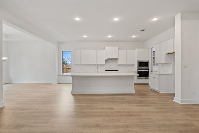 1701 Sauterne Dr, Leander, TX 78641 - kitchen with under cabinet range hood, stainless steel microwave, open floor plan, wall oven, and light countertops