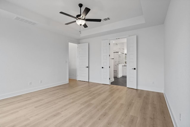 1701 Sauterne Dr, Leander, TX 78641 - unfurnished bedroom featuring a tray ceiling, visible vents, and light wood finished floors