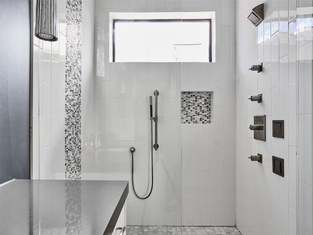 bathroom featuring a tile shower and a healthy amount of sunlight