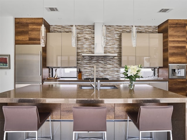 kitchen featuring a large island, sink, backsplash, pendant lighting, and a kitchen bar