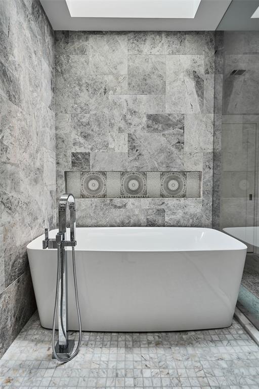 bathroom with a washtub and tile walls