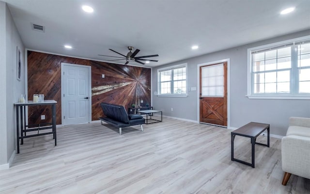 sitting room featuring wood walls, ceiling fan, and light wood-type flooring