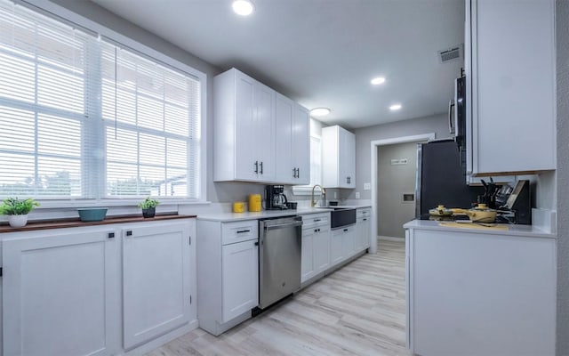 kitchen with white cabinets, appliances with stainless steel finishes, light hardwood / wood-style floors, and sink