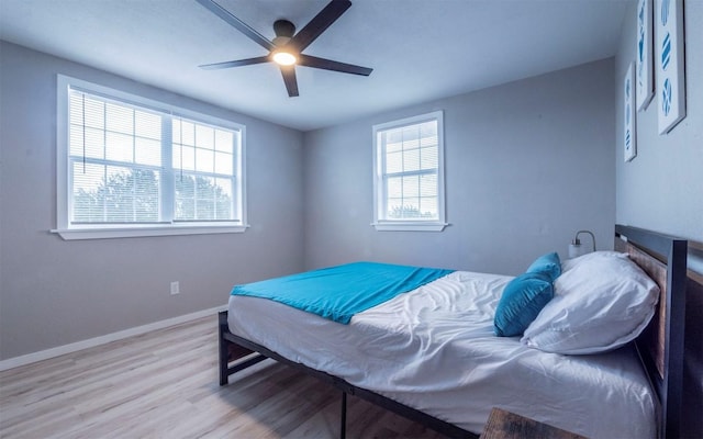 bedroom with ceiling fan, light wood-type flooring, and multiple windows