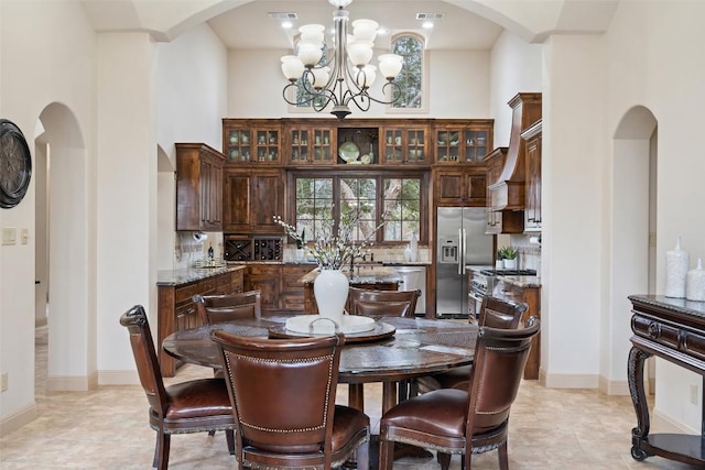 tiled dining area with a towering ceiling and a chandelier