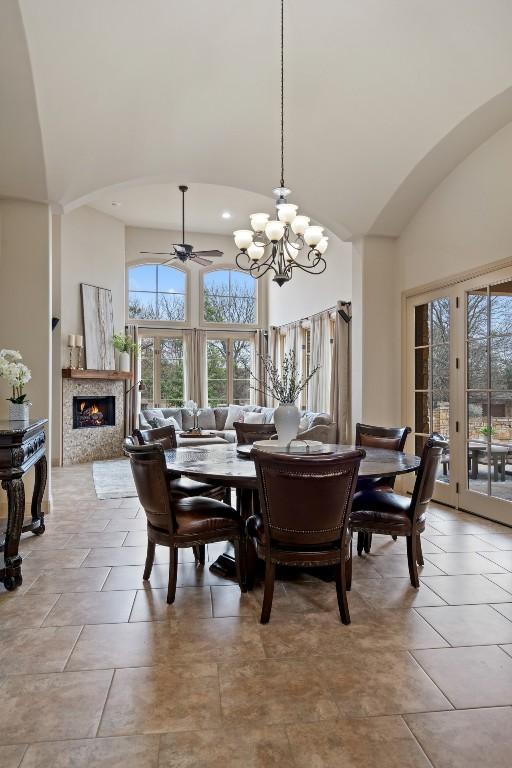 dining room featuring ceiling fan with notable chandelier and high vaulted ceiling