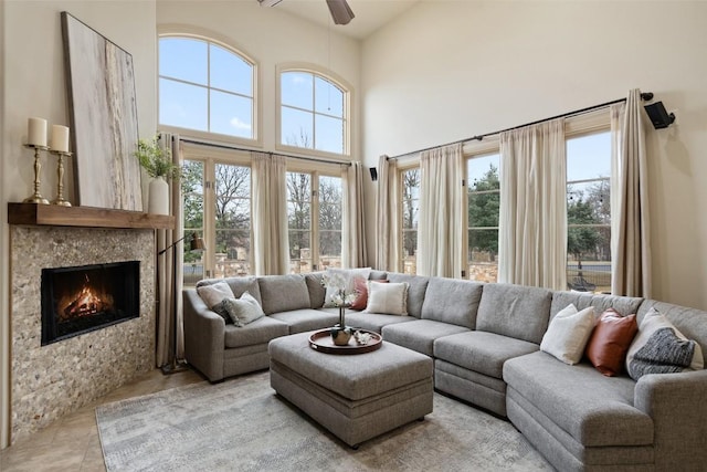 living room featuring ceiling fan, a healthy amount of sunlight, and a high ceiling