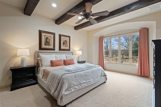 bedroom with ceiling fan, beamed ceiling, and light colored carpet