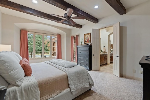 carpeted bedroom with beamed ceiling, connected bathroom, and ceiling fan