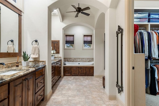 bathroom with a tub to relax in, ceiling fan, and vanity