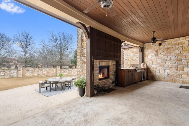 view of patio with area for grilling, a large fireplace, and ceiling fan