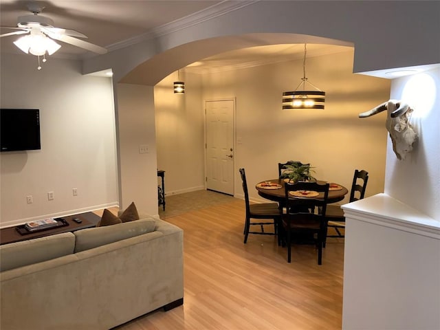 living room featuring ceiling fan with notable chandelier, ornamental molding, and light hardwood / wood-style flooring