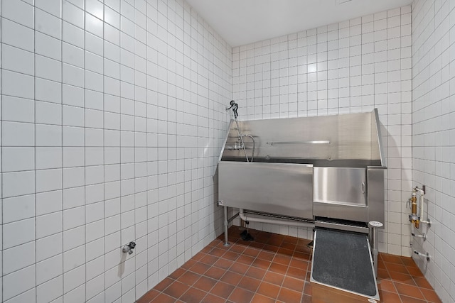 miscellaneous room featuring dark tile patterned flooring and tile walls