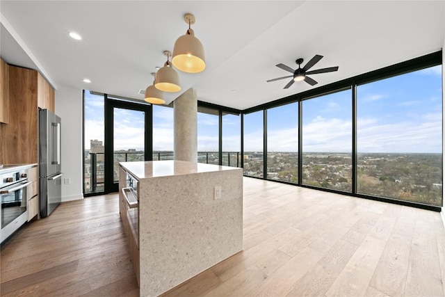 kitchen featuring decorative light fixtures, floor to ceiling windows, a kitchen island, and appliances with stainless steel finishes