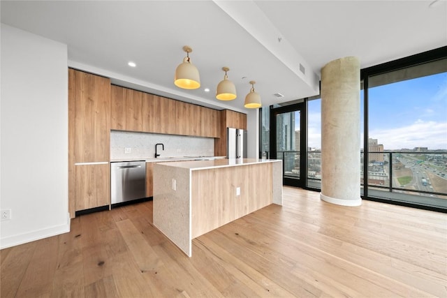 kitchen with a center island, expansive windows, light wood-type flooring, decorative light fixtures, and stainless steel appliances