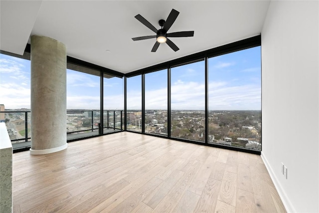 unfurnished room featuring light hardwood / wood-style floors, plenty of natural light, and a wall of windows