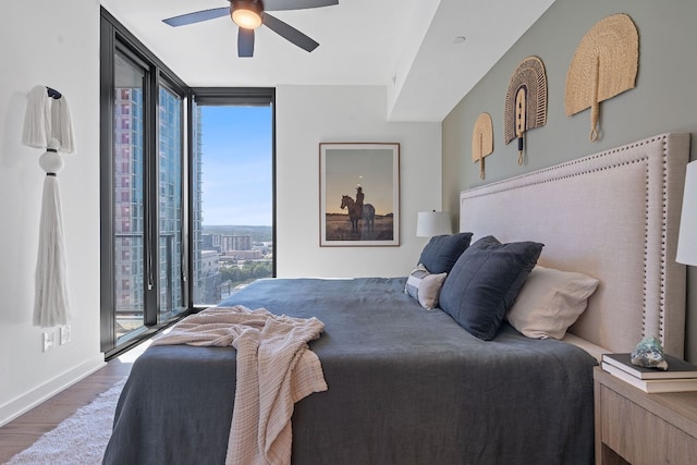 bedroom featuring ceiling fan, access to exterior, a wall of windows, and dark wood-type flooring