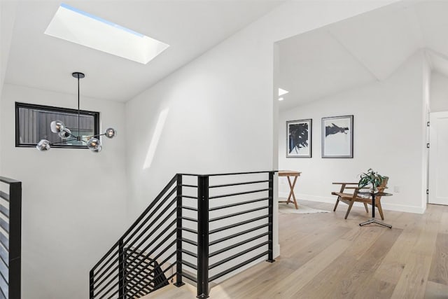 stairway featuring vaulted ceiling with skylight, a chandelier, and wood-type flooring