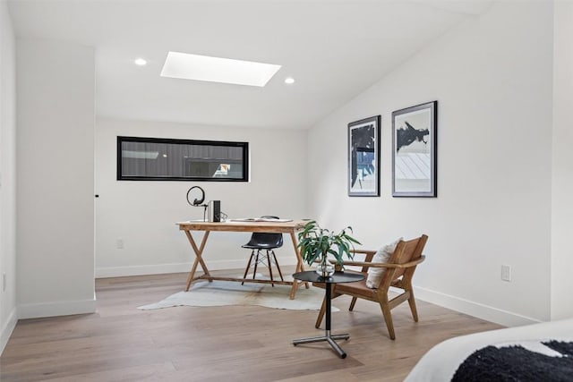 office with lofted ceiling with skylight and light hardwood / wood-style flooring