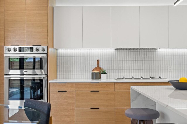 4505 Shoal Creek St, Austin, TX 78756 - kitchen with stainless steel double oven, modern cabinets, decorative backsplash, and stovetop