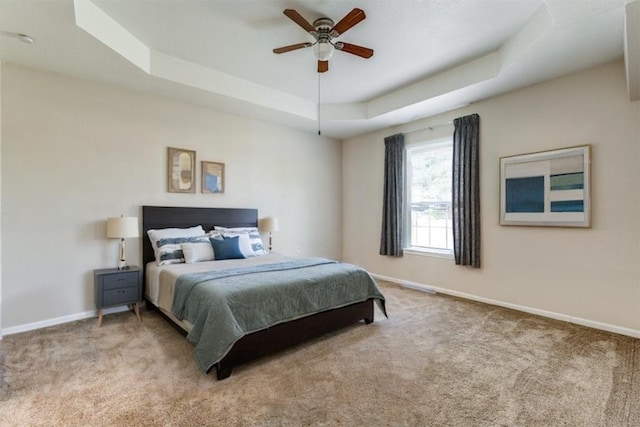 bedroom with a raised ceiling, carpet flooring, and baseboards