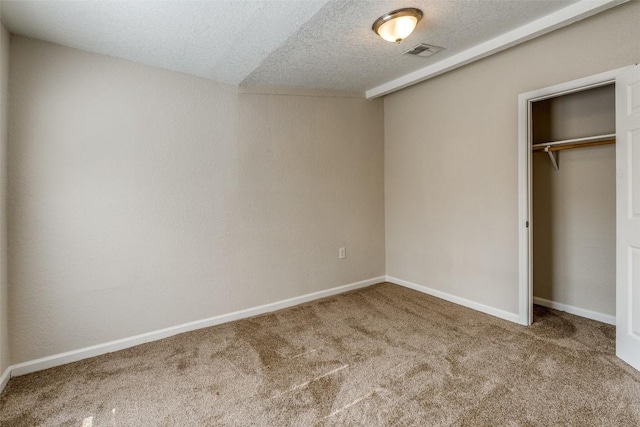 unfurnished bedroom featuring baseboards, visible vents, a textured ceiling, carpet flooring, and a closet