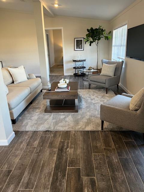 living area with lofted ceiling, baseboards, and wood tiled floor