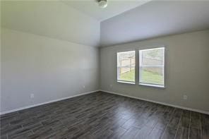 spare room featuring dark hardwood / wood-style floors and vaulted ceiling