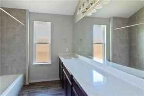 bathroom with vanity, hardwood / wood-style flooring, and tiled shower / bath