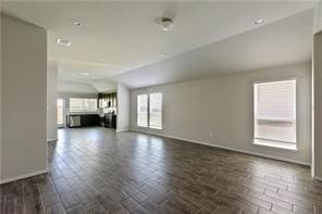 unfurnished living room featuring dark hardwood / wood-style flooring and vaulted ceiling