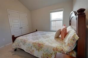 carpeted bedroom with a closet and lofted ceiling