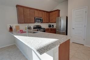 kitchen with kitchen peninsula, sink, stainless steel appliances, and lofted ceiling