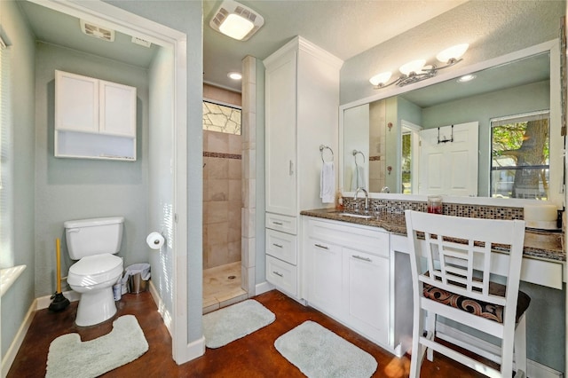 bathroom featuring toilet, a tile shower, and vanity