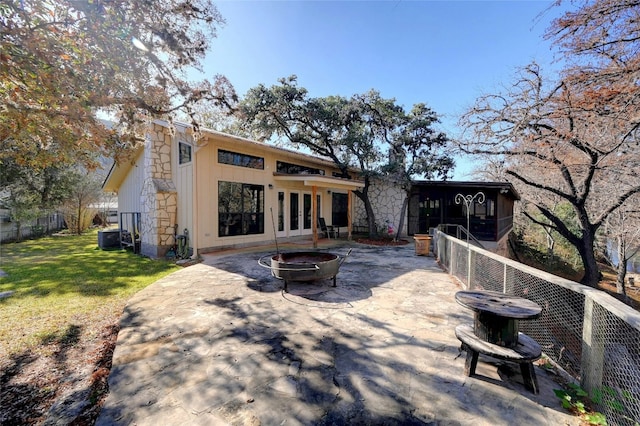 rear view of house with a fire pit, a patio, a lawn, and french doors