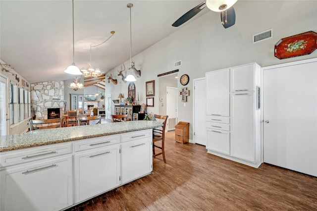 kitchen with a fireplace, white cabinetry, and hanging light fixtures